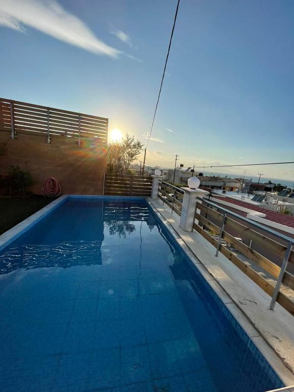 a swimming pool with the sun setting behind a fence at Claudia villa 2 in Agia Marina Nea Kydonias