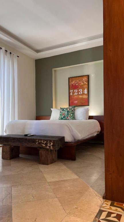 a bedroom with a large bed with a wooden bench at LUCA HOTEL Heritage Residences Signature Collection in Santo Domingo