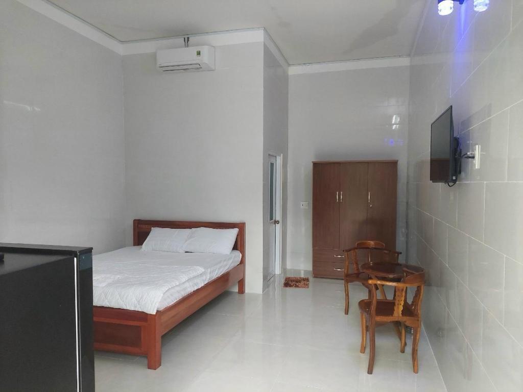 a bedroom with a bed and a table and a chair at Nhà Nghỉ Tốt Hơn in Phú Quốc