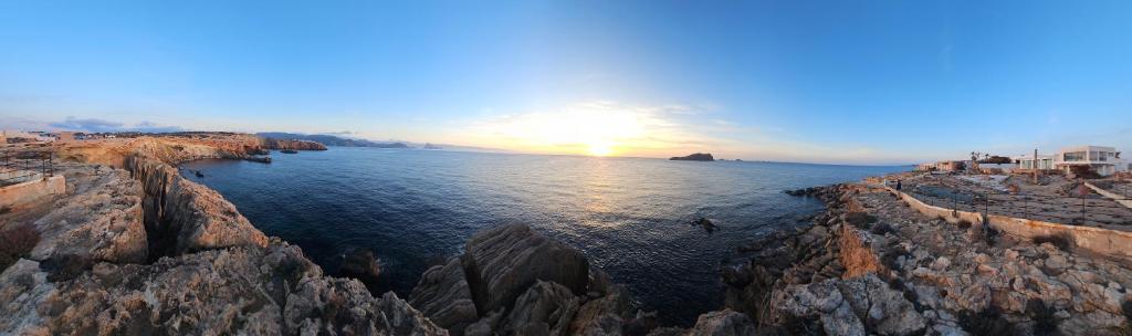 a view of the ocean with the sun setting over the rocks at Single Room in Ibiza Town