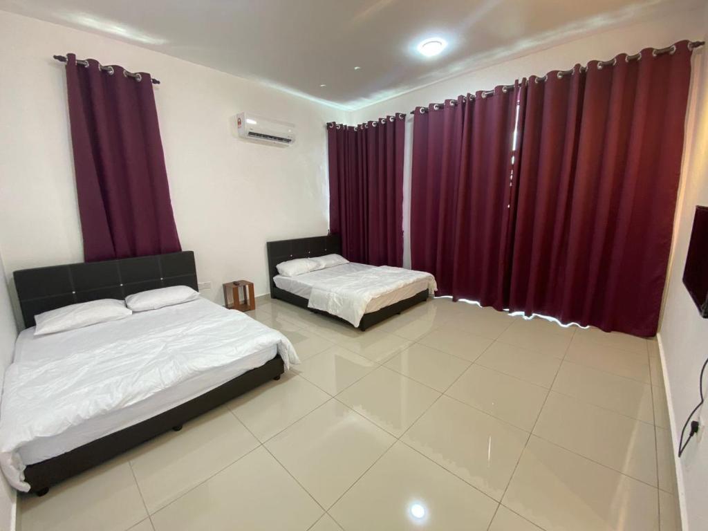 two beds in a room with red curtains at KSP Guest House in Melaka