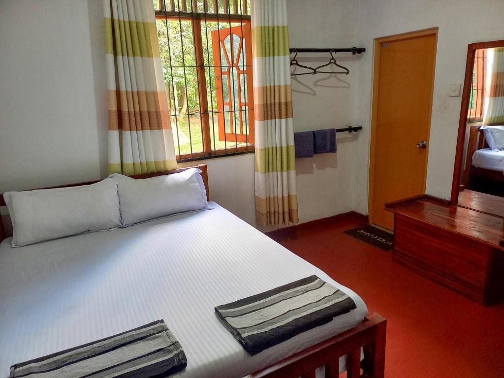 Un dormitorio con una gran cama blanca y una ventana en Kande Gedara Resort (කන්දෙ ගෙදර) en Monaragala