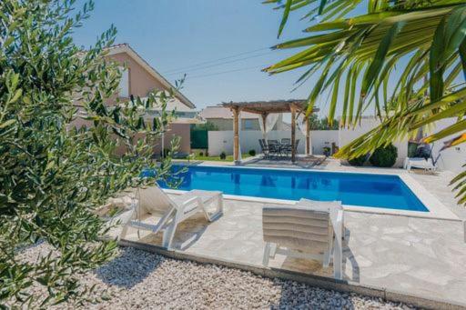 a swimming pool with two chairs and a gazebo at Villa Mell in Poličnik