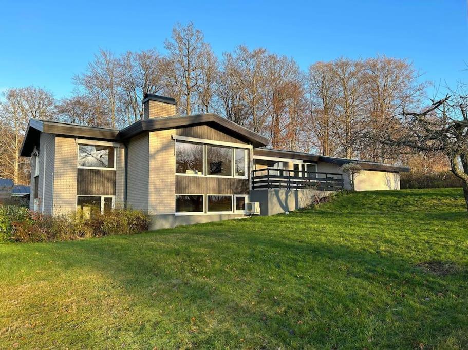 uma casa numa colina com um campo de relva em Big villa by the lake em Olofström