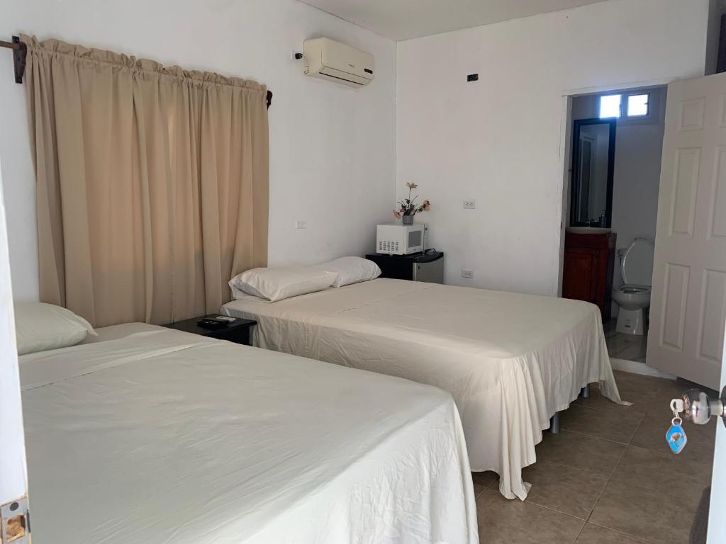 duas camas num quarto com lençóis brancos em Complejo Deportivo Wilson Palacios em La Ceiba