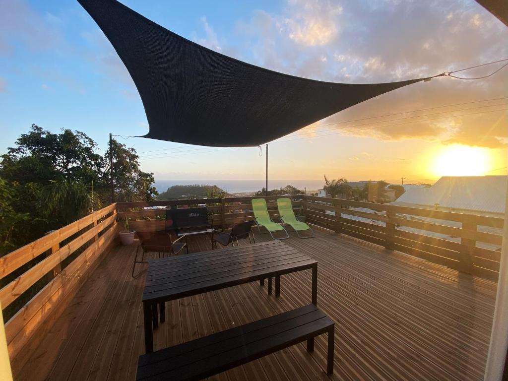 a deck with a table and chairs and a sunset at Maison vue mer La Réunion in Saint-Joseph