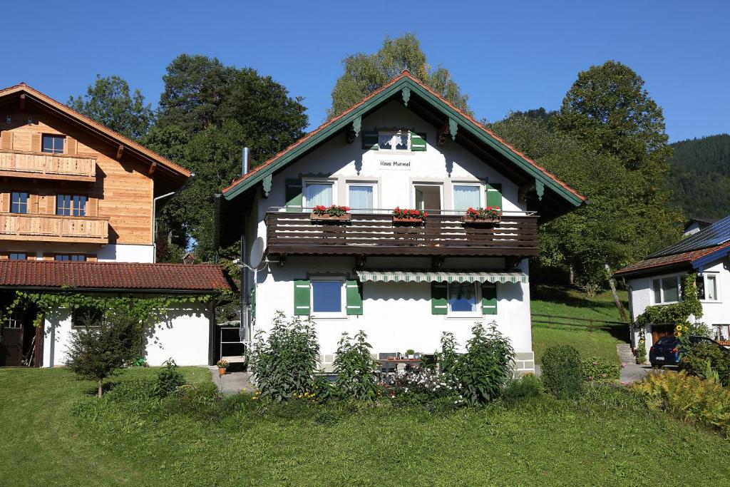 a white house with a balcony with flowers on it at Ferienhaus Murmel in Ruhpolding