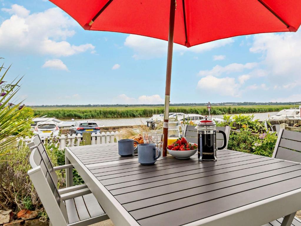 a table with an umbrella and a bowl of fruit at 3 Bed in Reedham 47835 in Haddiscoe