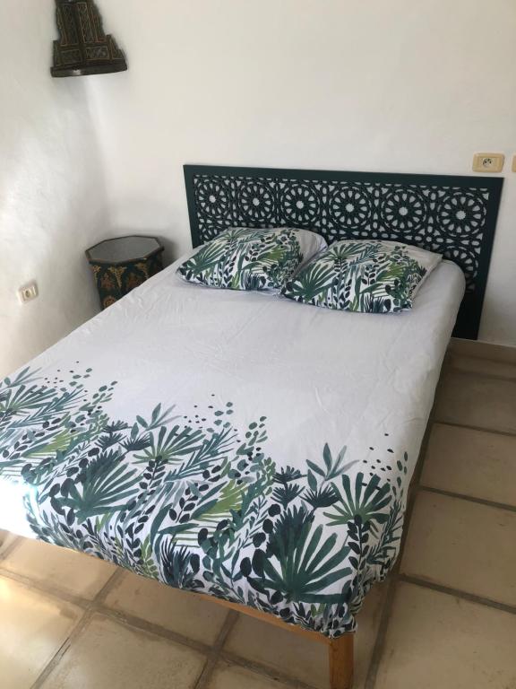 a bed with a black and white comforter and pillows at RESIDENCE DAR YASMINa in Mezraya