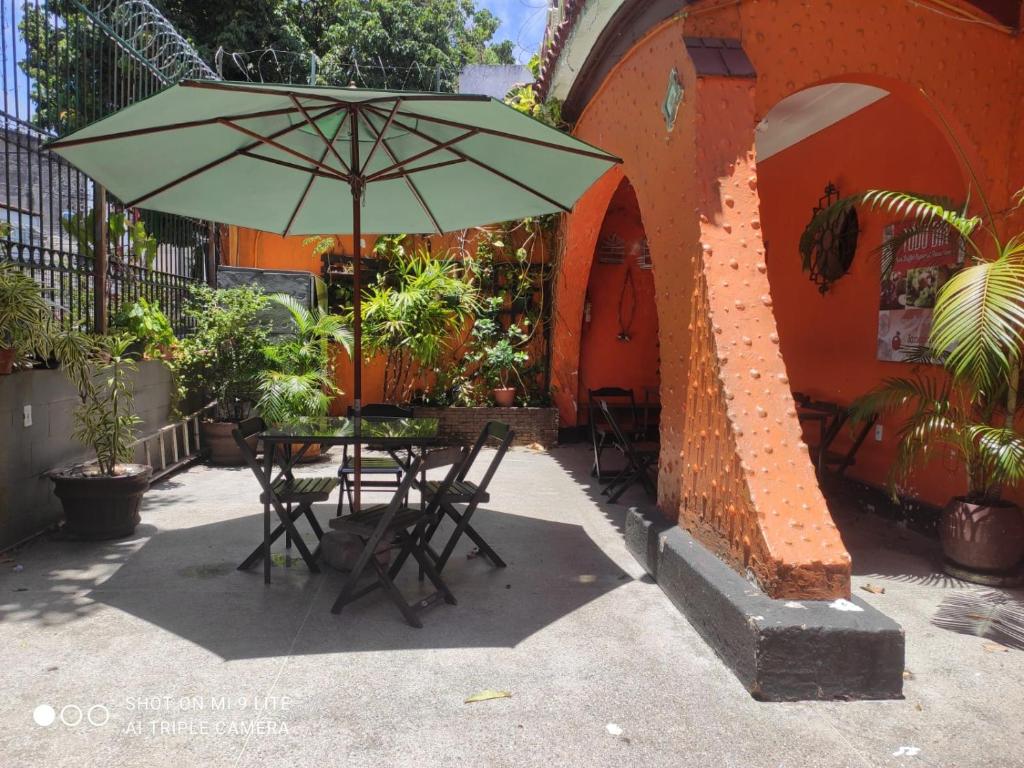 uma mesa e cadeiras com um guarda-sol em frente a um edifício em Pousada San Salvador em Salvador