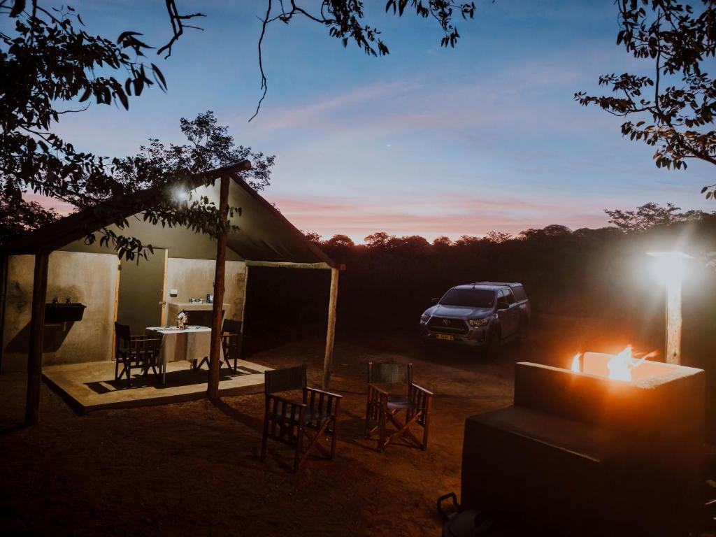 a truck parked next to a house with a table and chairs at Mountain Peak Game Lodge and Camping in Outjo