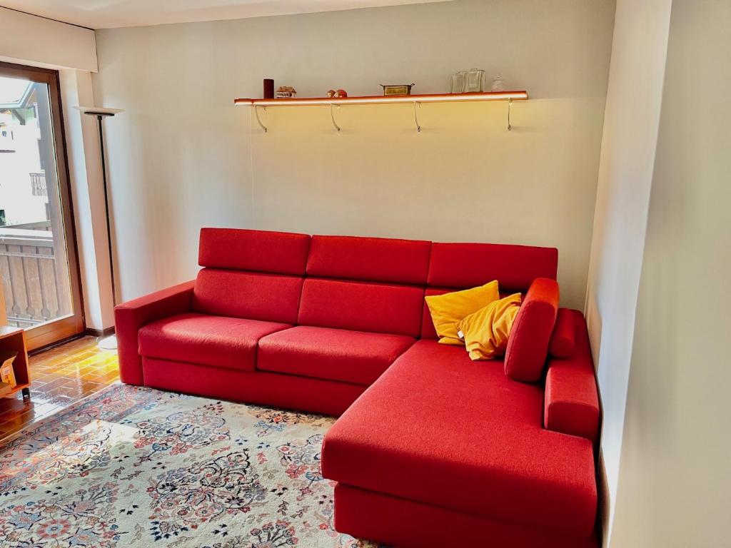 un sofá rojo con almohadas amarillas en la sala de estar. en Appartamento per Famiglie, 6 posti, in centro ad Asiago, en Asiago