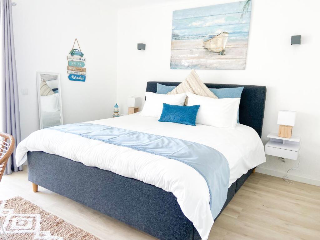 Carvoeiro Beach Appartment في كارفويرو: غرفة نوم بسرير كبير ومخدات زرقاء وبيضاء