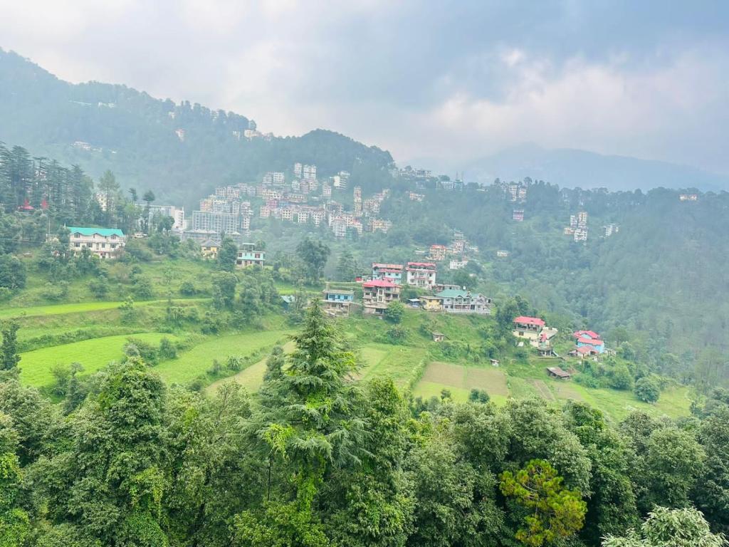 a town on a hill with trees and buildings at The Asha Residency - Majestic Mountain View , Shimla in Shimla
