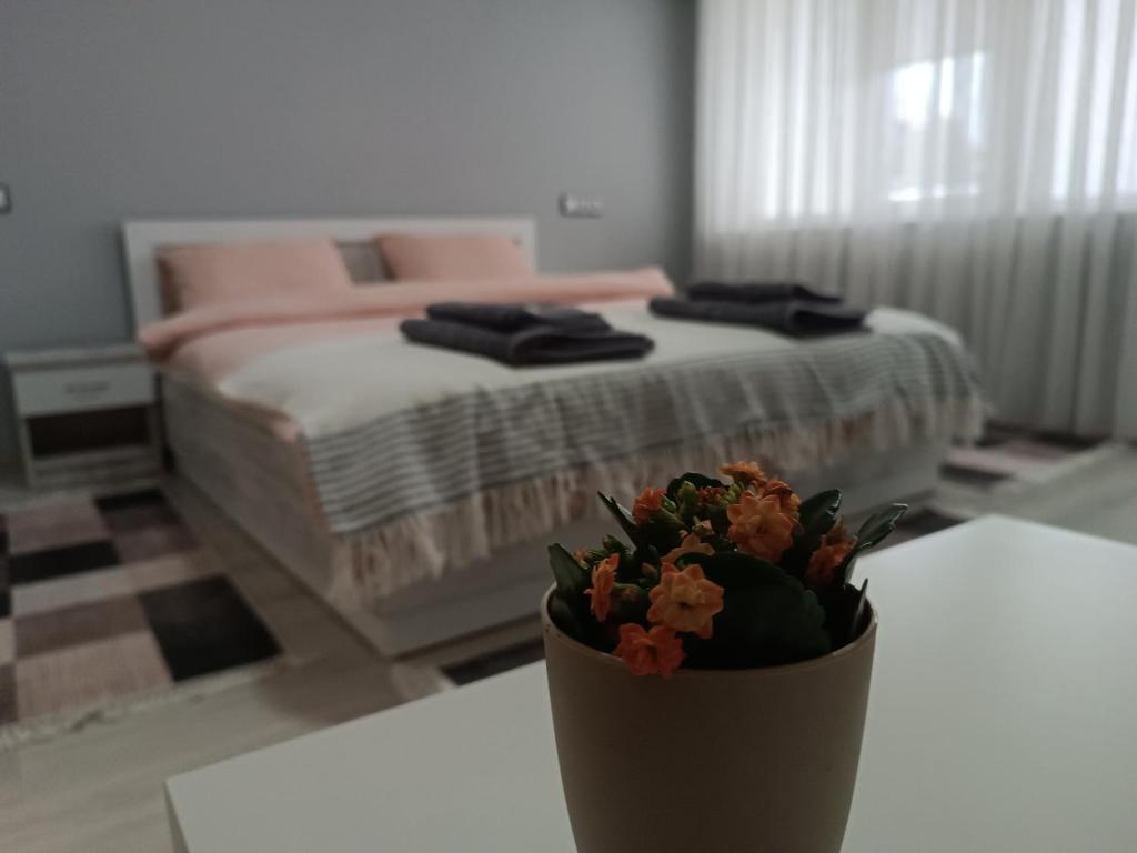 a bedroom with a bed and a vase with flowers on a table at City Apartment in Gotse Delchev