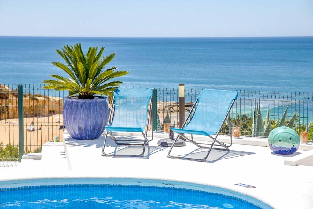 two chairs and a potted plant next to a pool at Villa de la Plage in Albufeira