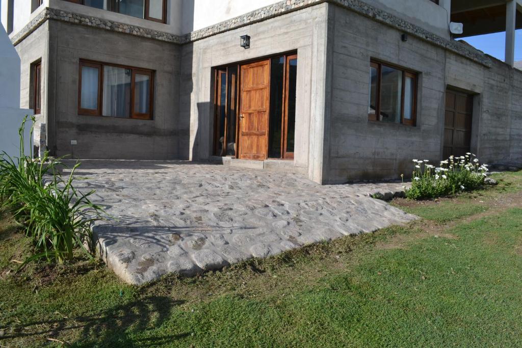 a house with a wooden door and a yard at Aires del Alto - casas in Tafí del Valle