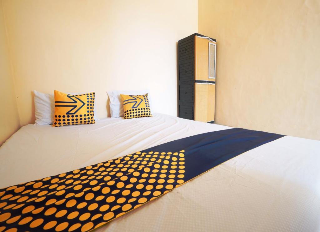- une chambre dotée d'un lit avec des oreillers jaune polka dot dans l'établissement SPOT ON 93685 Homestay Bu Sun Syariah, à Sidoarjo