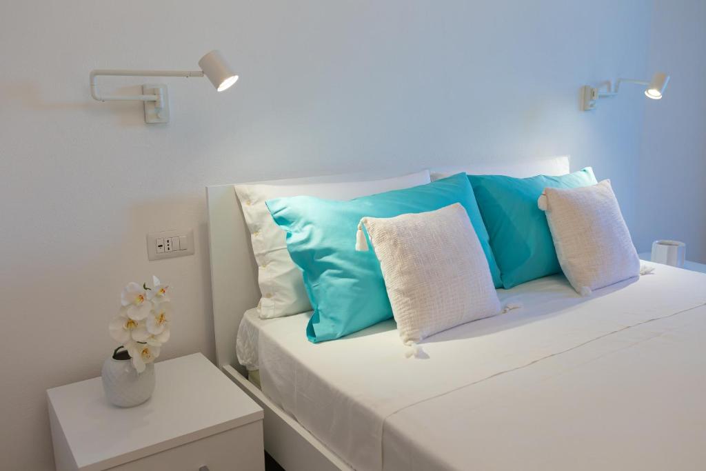 uma cama branca com almofadas azuis e brancas em Estia Suites em Villasimius