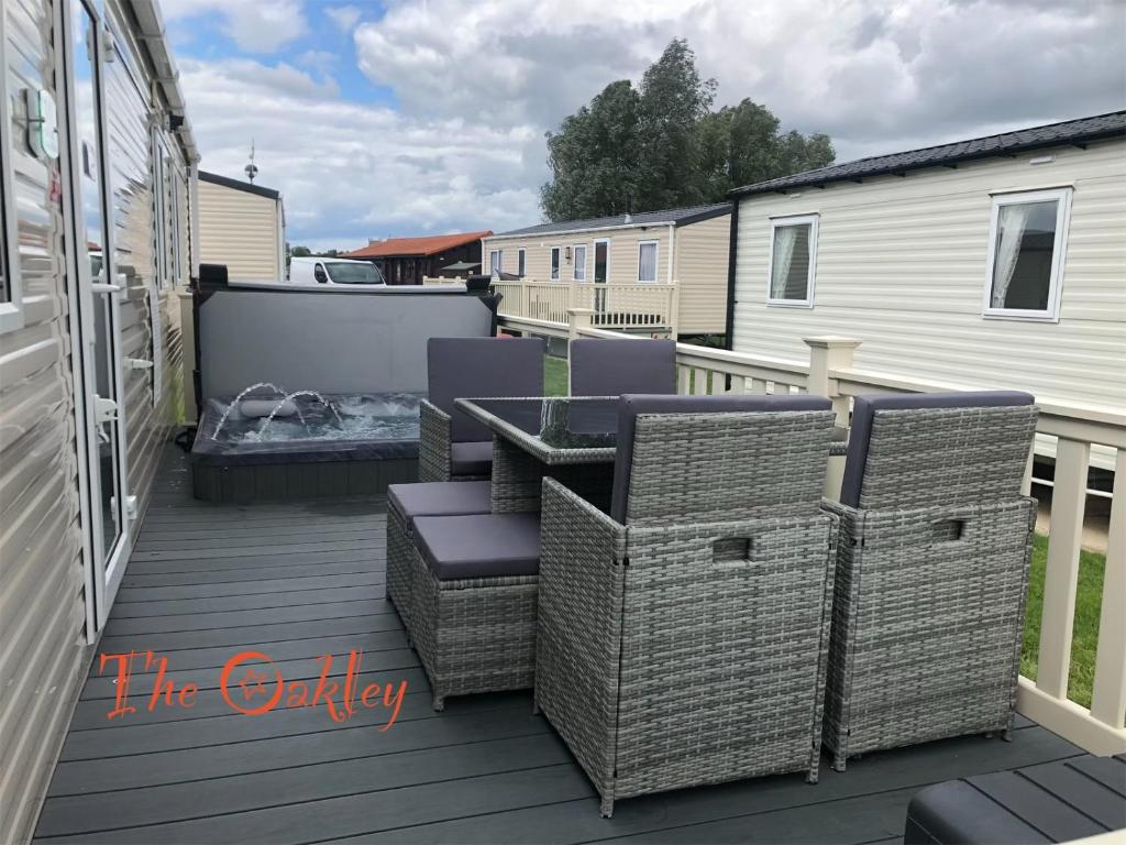 a patio with wicker chairs and a grill on a deck at Tattershall Lakes The Oakley Caravan 8 berth, Hot tub & WiFi in Tattershall