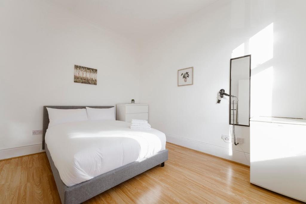 Habitación blanca con cama y nevera. en Stratford Double Rooms - 29 en Londres