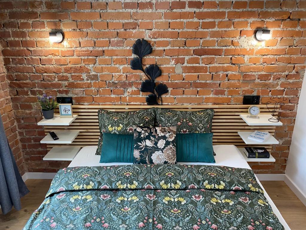 a bed in a room with a brick wall at Konarskiego Residence in Kraków