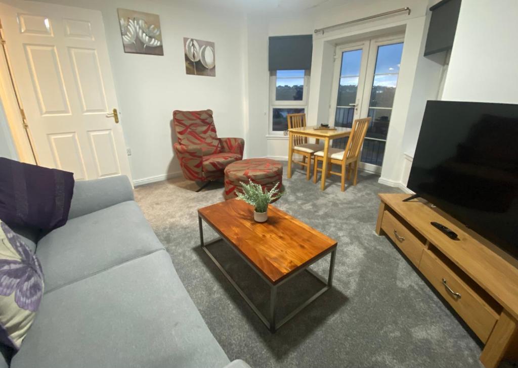 ein Wohnzimmer mit einem Sofa, einem TV und einem Tisch in der Unterkunft Duloch Bridge View in Dunfermline