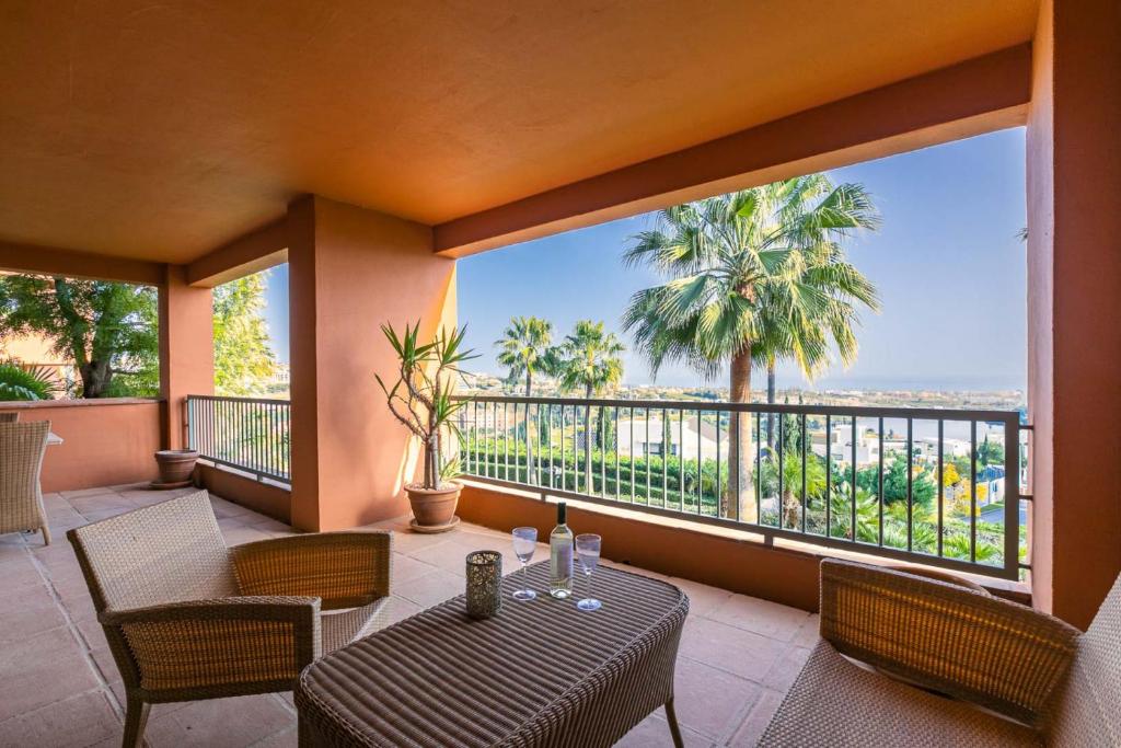 un balcone con tavolo, sedie e ampia finestra di Royal Flamingos Sea View Apartman a Estepona