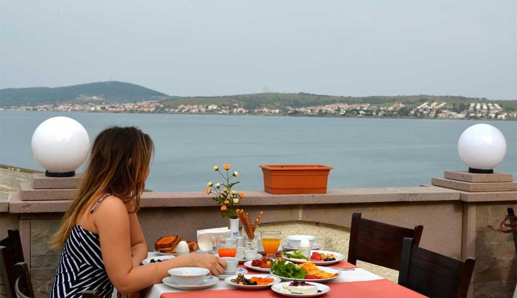 una mujer sentada en una mesa con un plato de comida en Ayvalık Palas Hotel, en Ayvalık