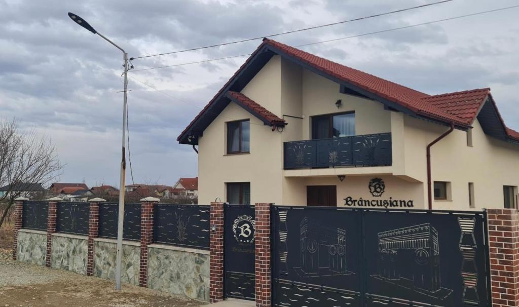 a house with a fence in front of it at Casa Brâncușiana in Târgu Jiu