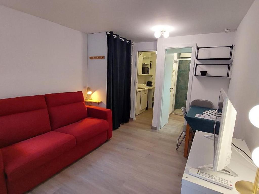 a living room with a red couch and a table at Studio Courchevel, 1 pièce, 2 personnes - FR-1-514-80 in Courchevel