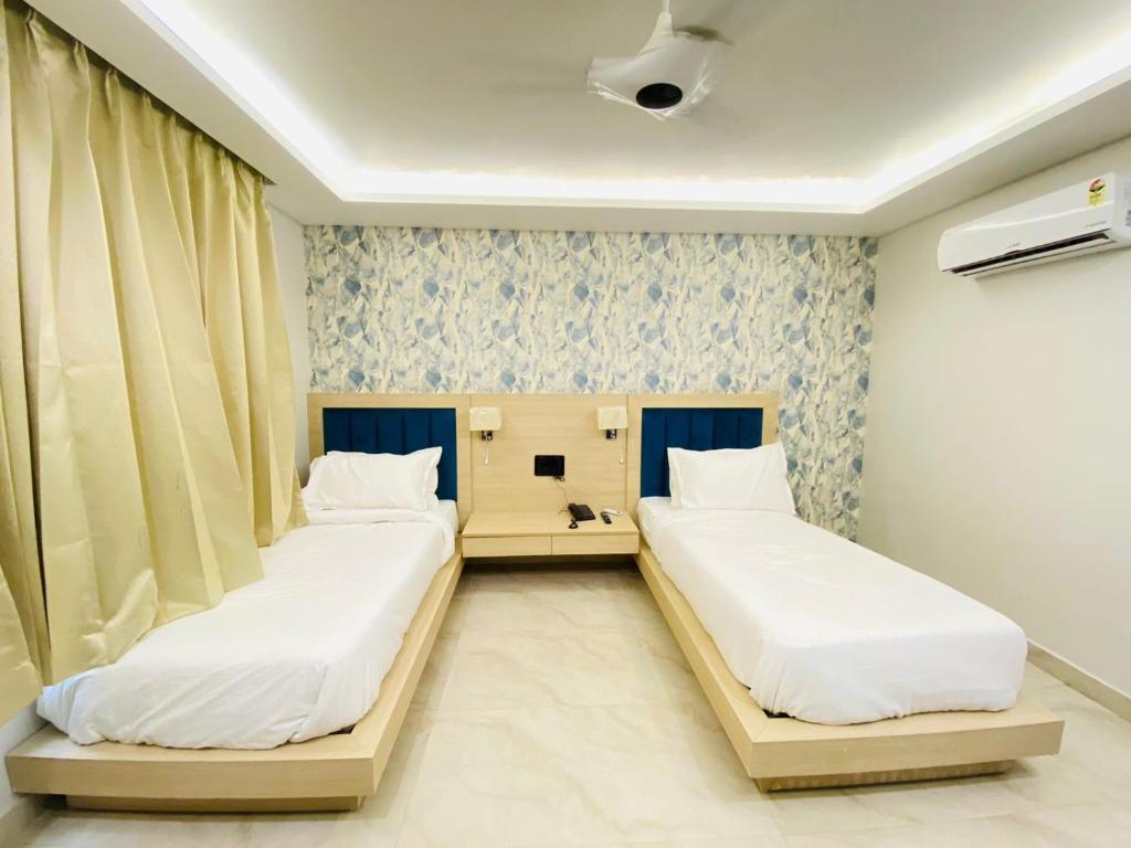 two beds in a hospital room with curtains at Hotel Holiday Grand in Greater Noida