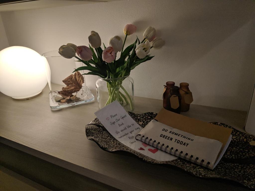 een tafel met een vaas met bloemen en een boek bij Gaia St Paul's Bay Modern Cosy Apartment in St Paul's Bay