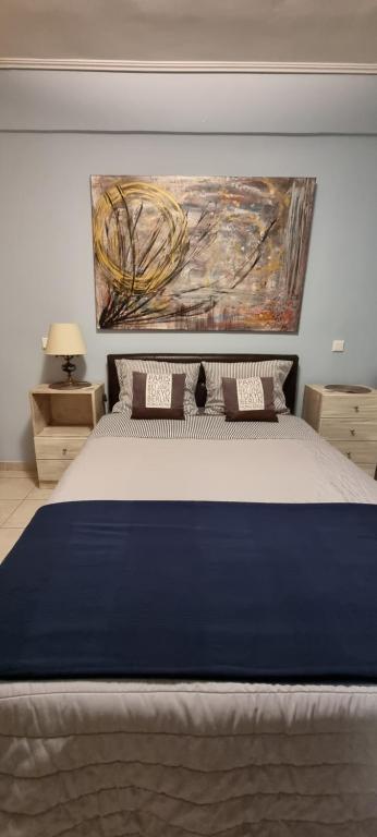 a bedroom with a large bed with a painting on the wall at Μεγάλος χώρος με Γυμναστήριο-Χαμάμ-Κρεβάτι-Γραφείο in Krionérion