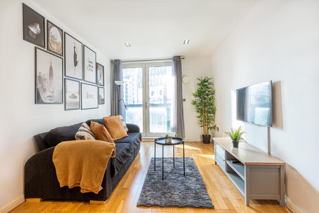 a living room with a couch and a tv at Corporate Canary Suite in London