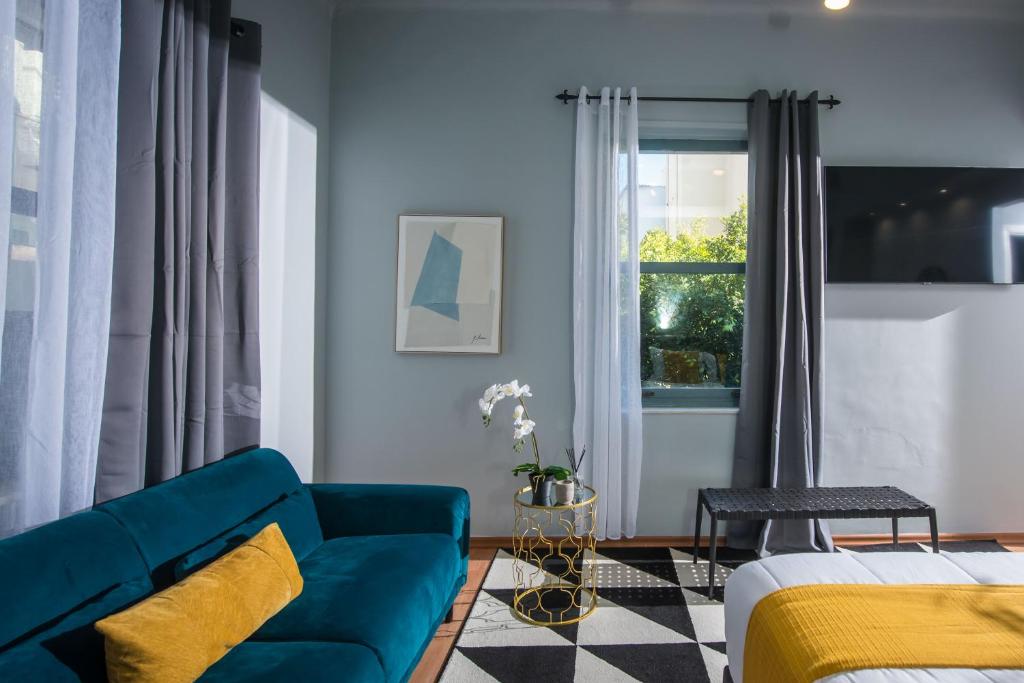 a living room with a blue couch and a window at Korai Suites by Good Life in Heraklio