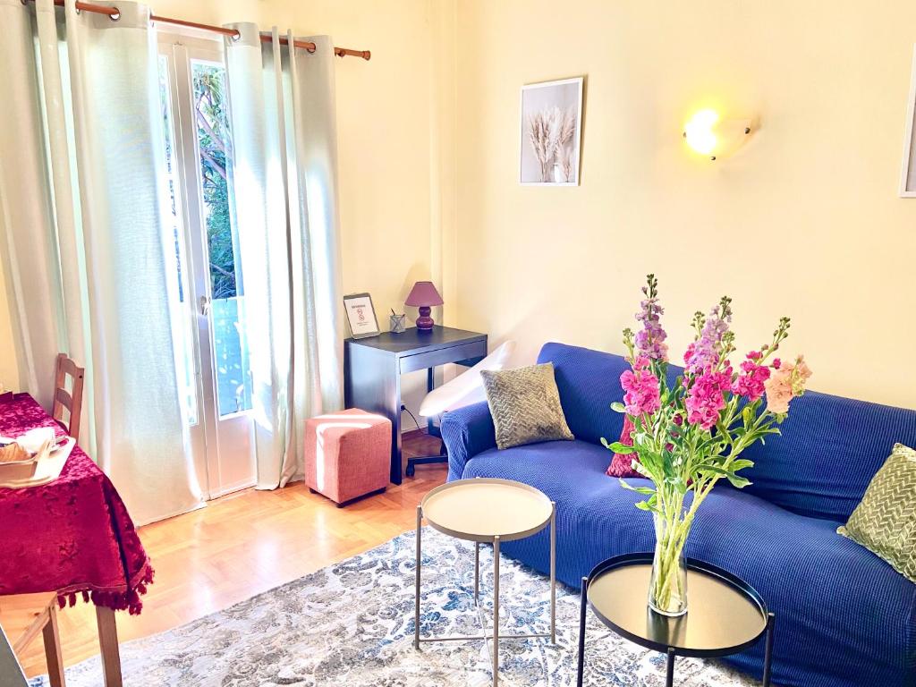 a living room with a blue couch and a vase of flowers at Fenia's Apartment in Athens