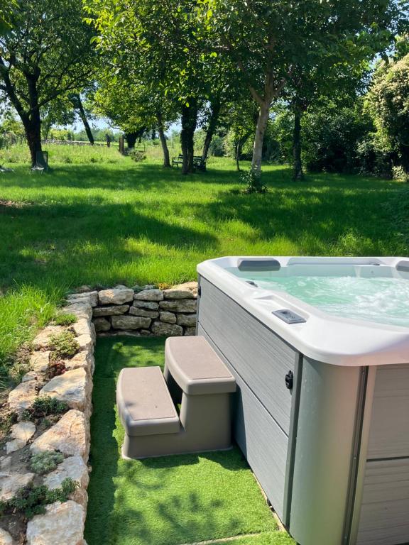 a hot tub with a bench next to a field at Borostyán Porta Lesencetomaj in Lesencetomaj