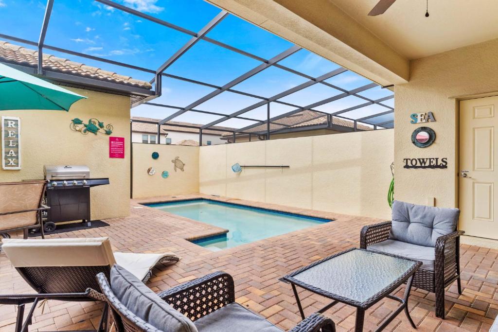 a patio with a pool with chairs and a table at Townhome with Private Pool, BBQ & FREE Waterpark in Kissimmee