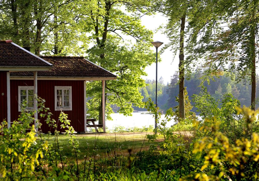 a small red house in the middle of a forest at Urshult Camping in Urshult