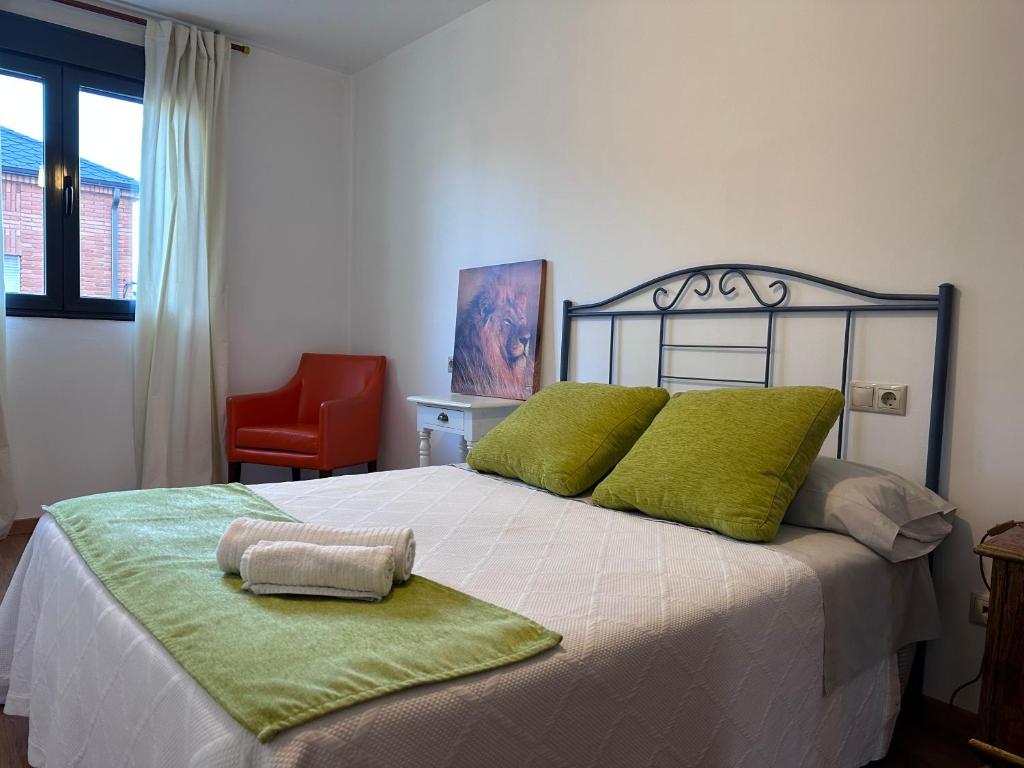 um quarto com uma cama com almofadas verdes e uma cadeira vermelha em Suite Rigel em Ponferrada