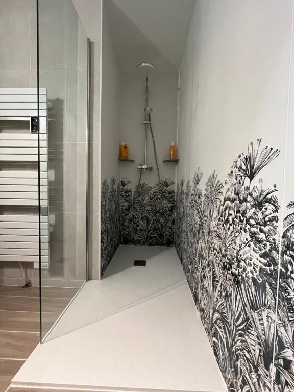 a bathroom with a shower with plants on the wall at Le petit coin de Paradis in Varaville