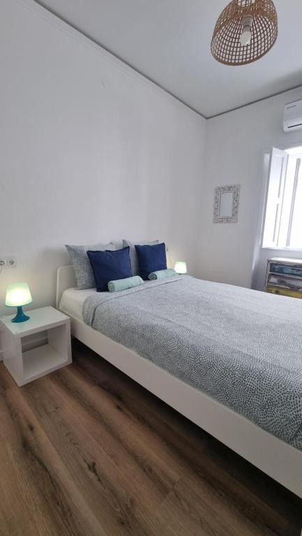 a white bedroom with a large bed with blue pillows at Happen!ng in Faro