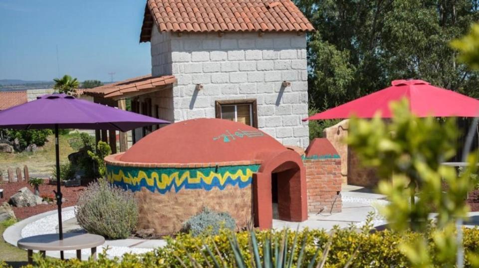 a small building with a table and an umbrella at Cabañas Jassí in Querétaro