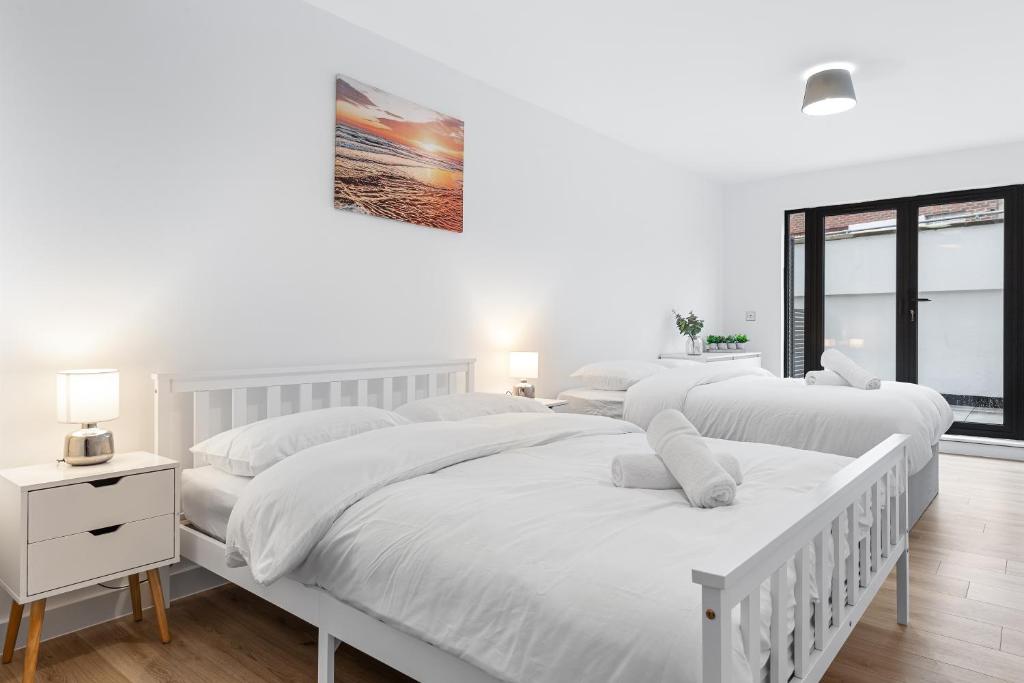una camera bianca con 3 letti e una finestra di Three Bedroom In Heart Of Central London MR4 a Londra