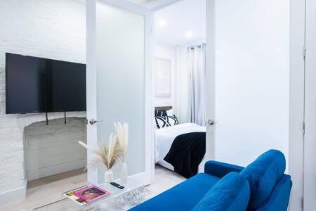 uma sala de estar com um sofá azul e uma televisão em Brand new 2BR 1Bath East Village em Nova York