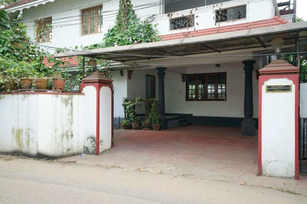 une maison blanche avec piliers rouges et une cour dans l'établissement Good Palace, à Ernakulam