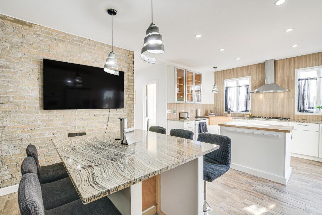a kitchen with a table with chairs and a tv on a brick wall at Bright Chicago Home with Backyard Less Than 5 Mi to Downtown in Chicago