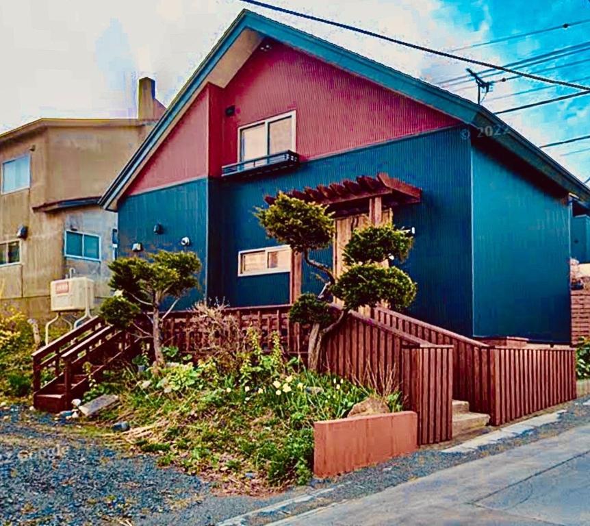 uma casa azul e vermelha com uma cerca em frente em Populasunupuri - Vacation STAY 62945v em Otaru