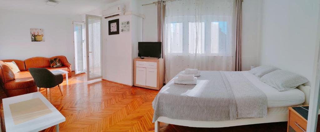 ein Schlafzimmer mit einem Bett, einem Sofa und einem TV in der Unterkunft Apartmani Bojana in Rovinj